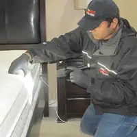 Bed bug inspection technician checking a mattress and bed frame for signs of infestation in Chandler, AZ