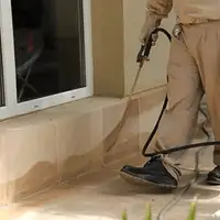 General pest control technician spraying exterior perimeter around a home in Chandler, AZ