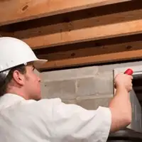 Termite inspection technician checking a basement wall and framing for termite activity in Chandler, AZ